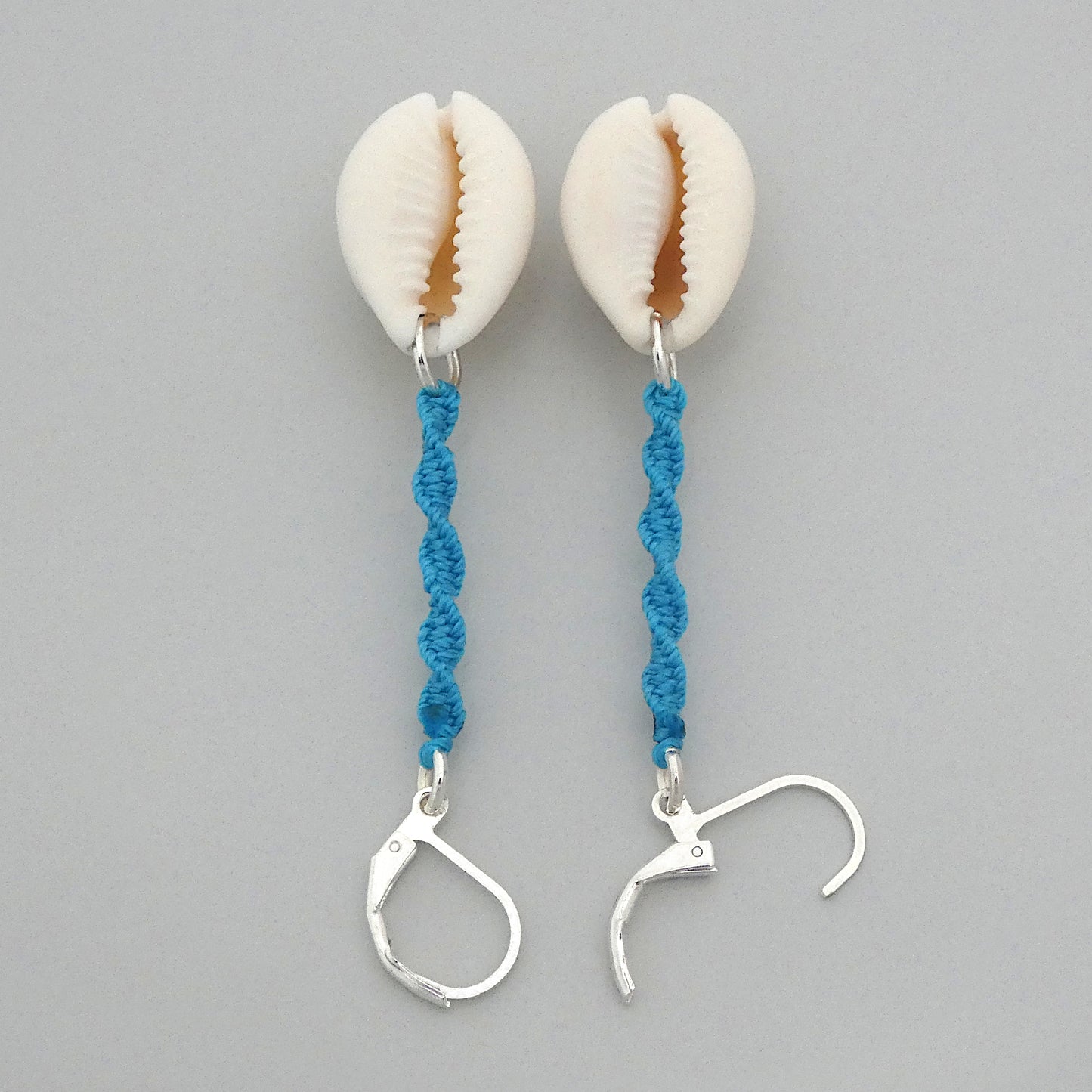 Silver plated leverback earrings with cowrie shells and blue macramé twist detail.