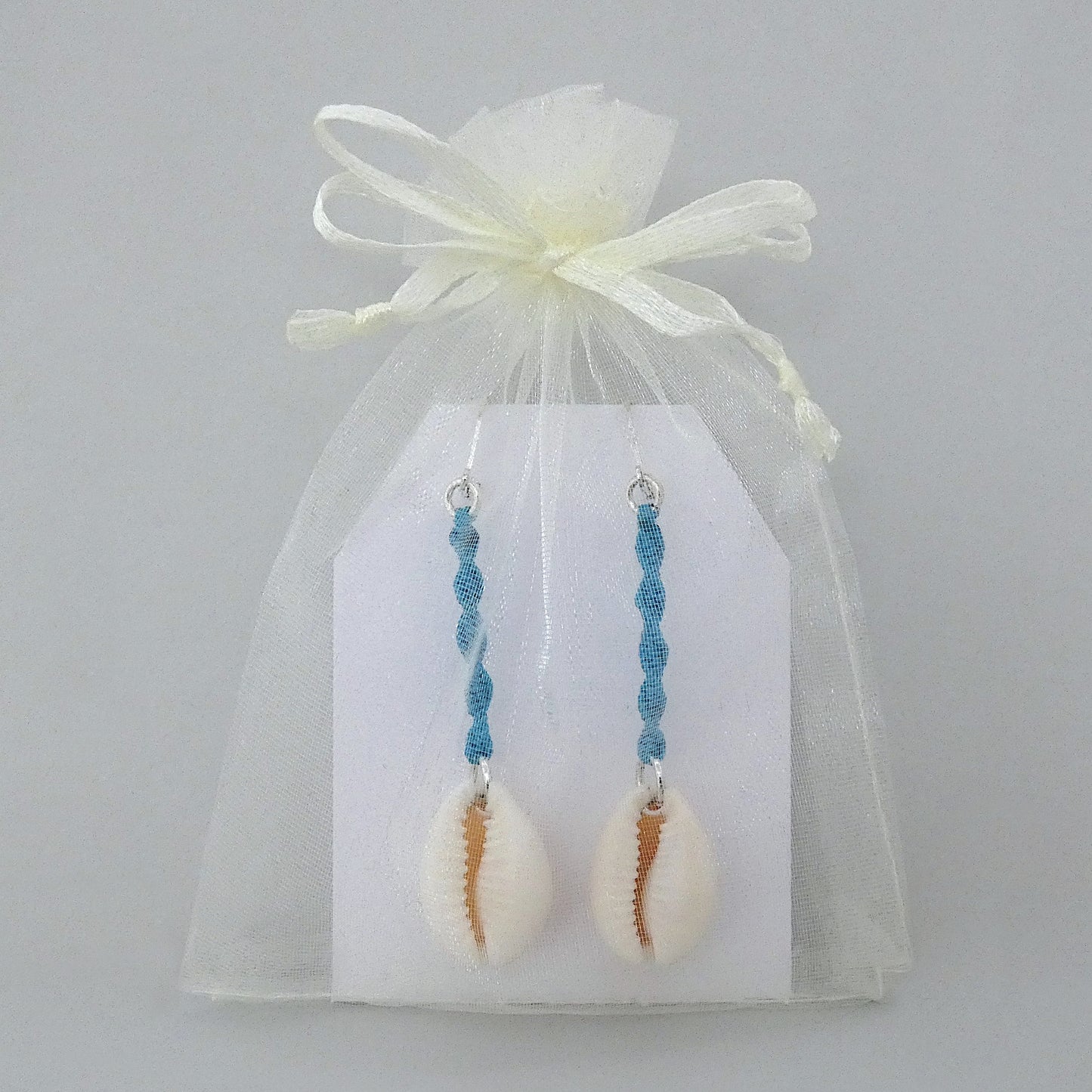 Silver plated leverback earrings with cowrie shells and blue macramé twist detail.