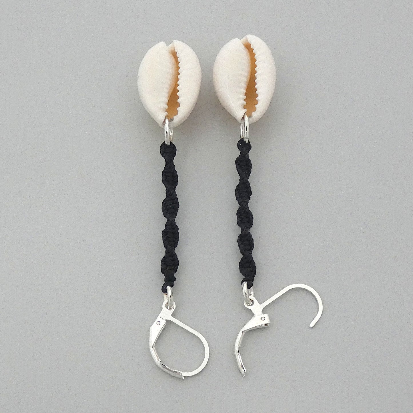 Silver plated leverback earrings with cowrie shells and black macramé twist detail.