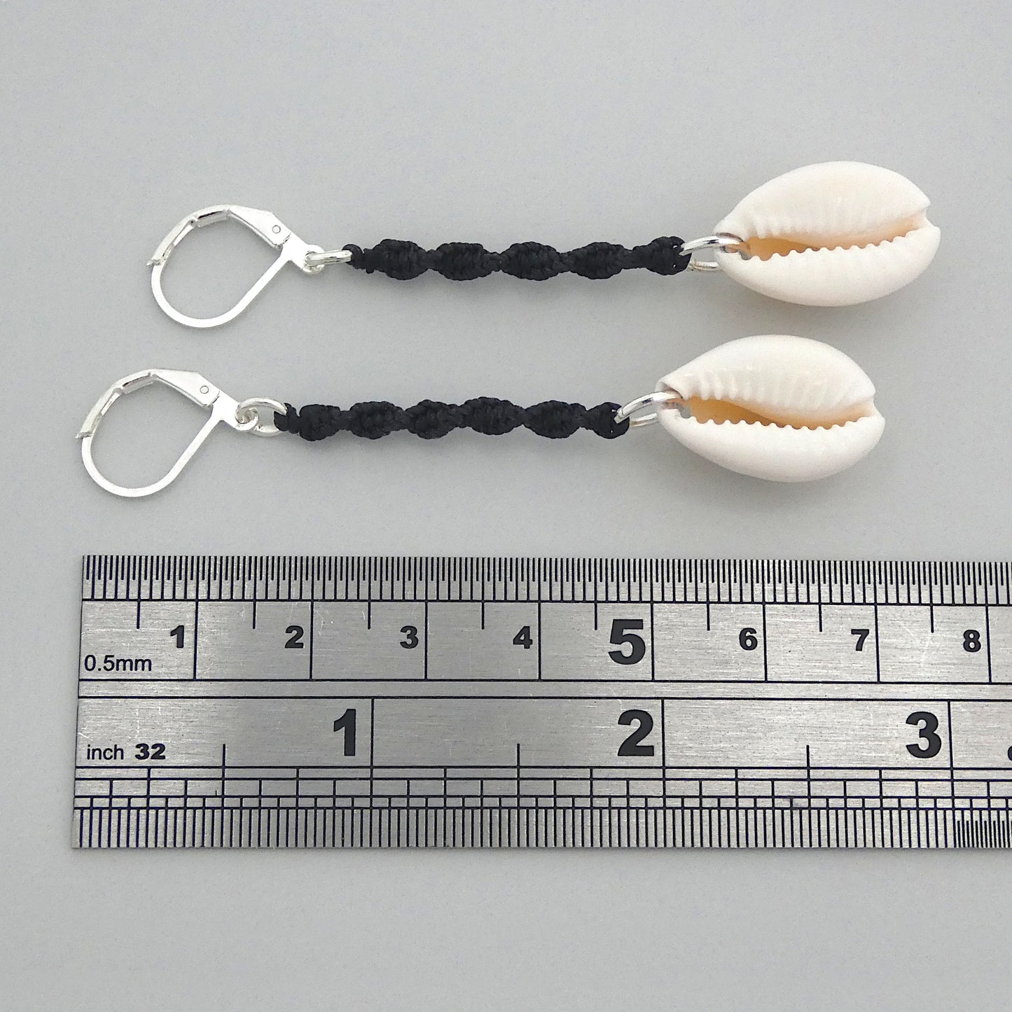 Silver plated leverback earrings with cowrie shells and black macramé twist detail.