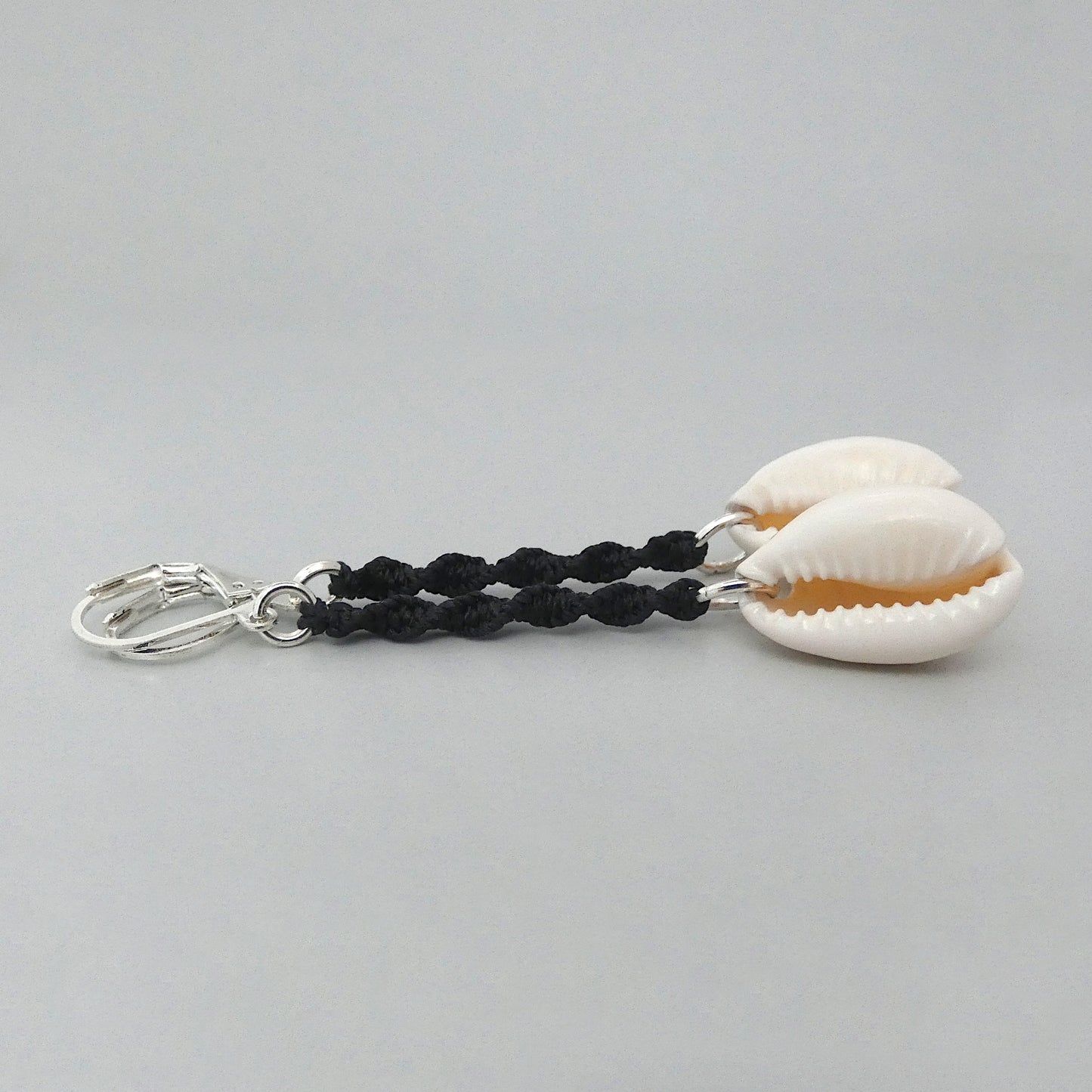 Silver plated leverback earrings with cowrie shells and black macramé twist detail.