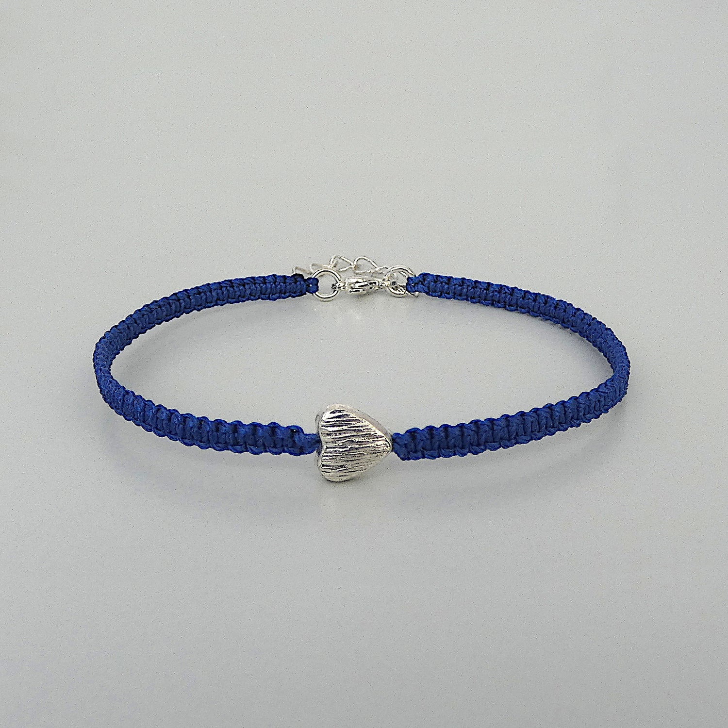 Royal blue seven inch macramé bracelet with silver plated textured heart charm, lobster clasp and one inch extender chain.