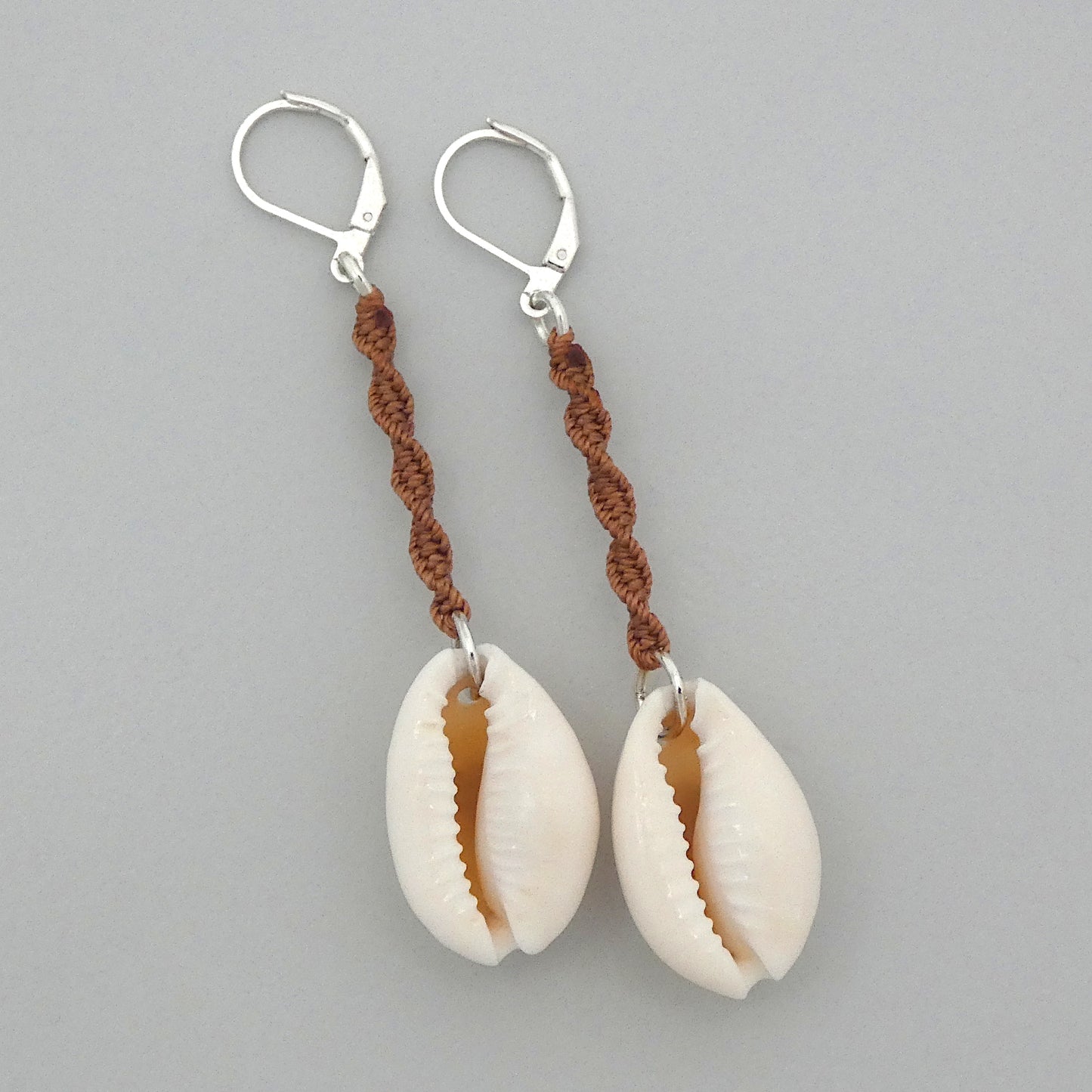 Silver plated leverback earrings with cowrie shells and copper coloured macramé twist detail.