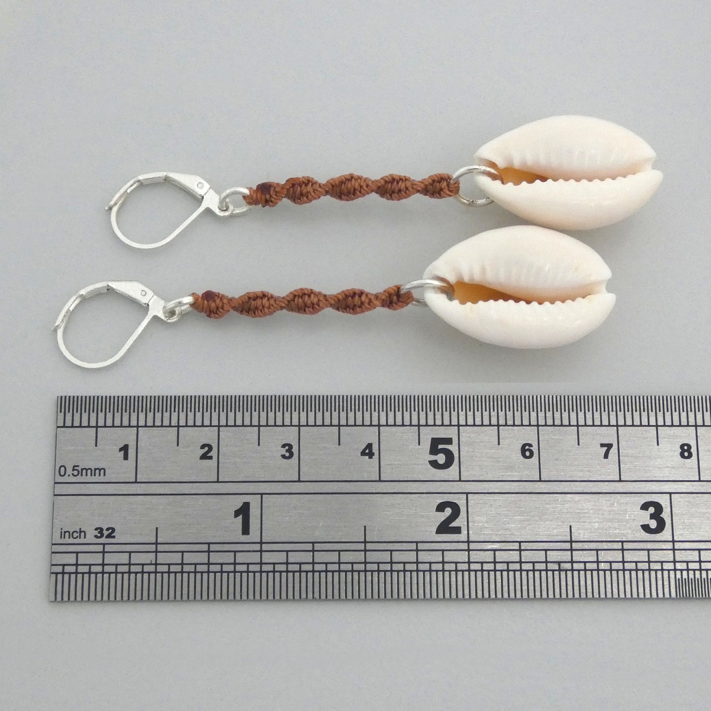 Silver plated leverback earrings with cowrie shells and copper coloured macramé twist detail.