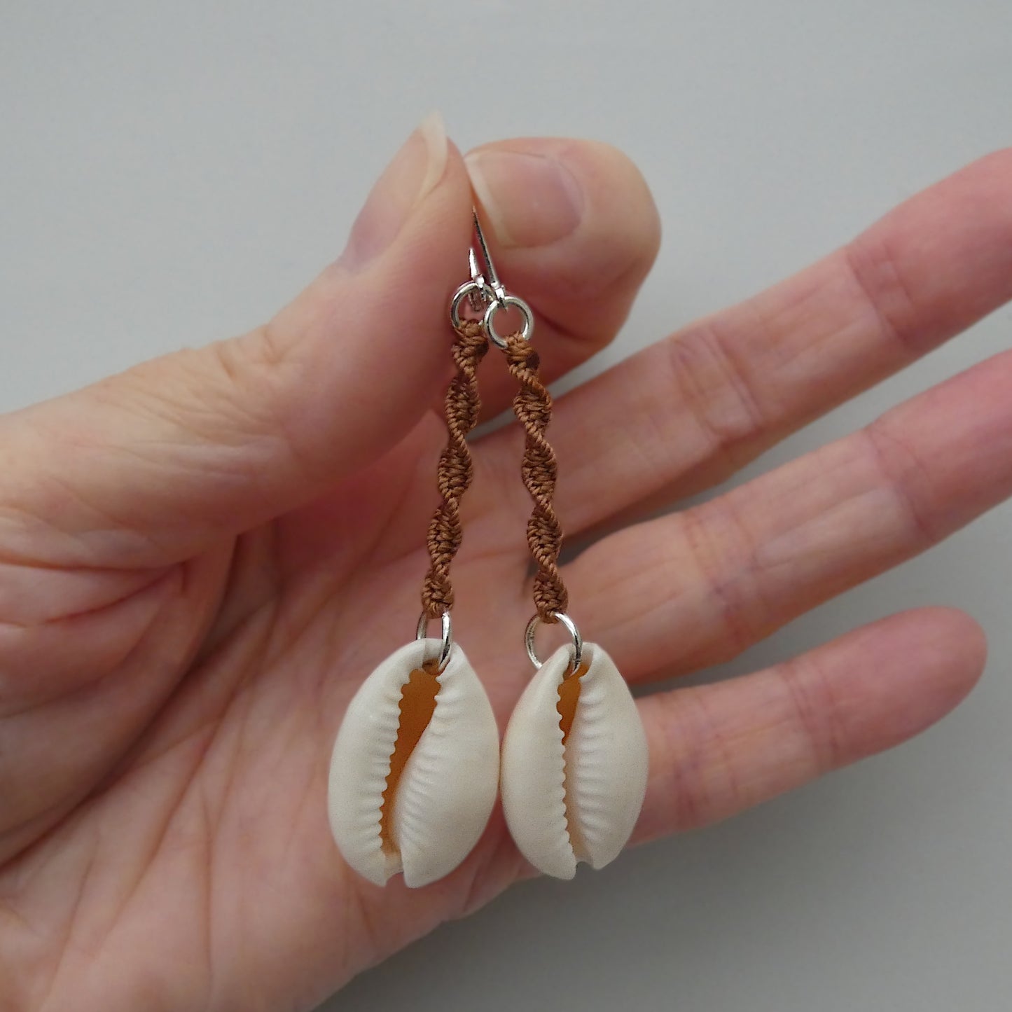 Silver plated leverback earrings with cowrie shells and copper coloured macramé twist detail.