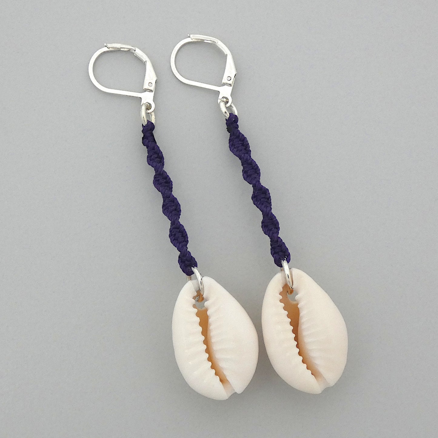 Silver plated leverback earrings with cowrie shells and dark purple macramé twist detail.