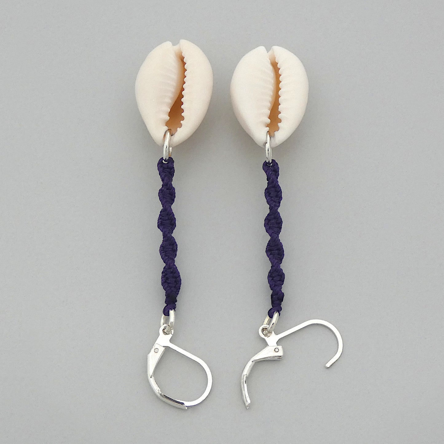 Silver plated leverback earrings with cowrie shells and dark purple macramé twist detail.