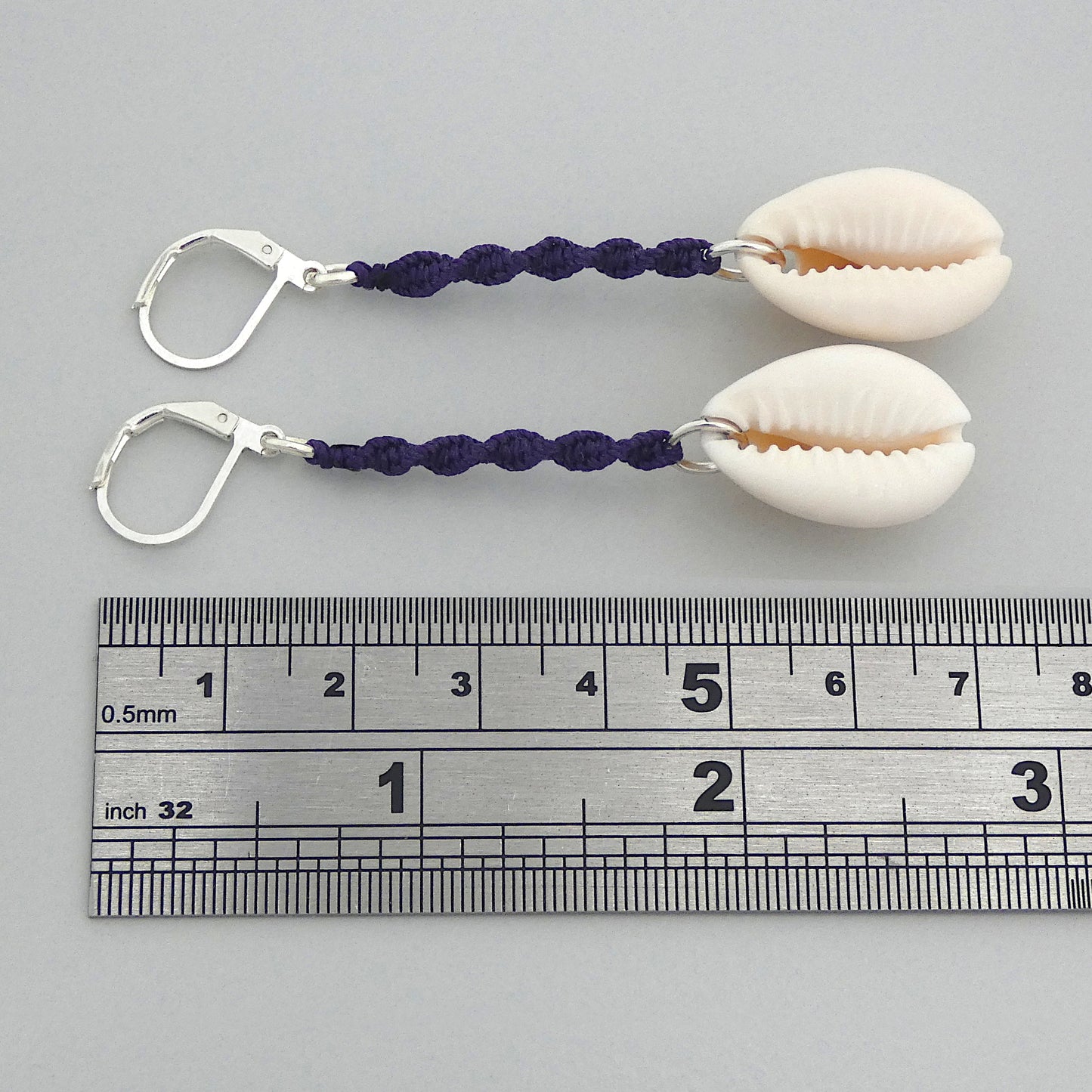 Silver plated leverback earrings with cowrie shells and dark purple macramé twist detail.