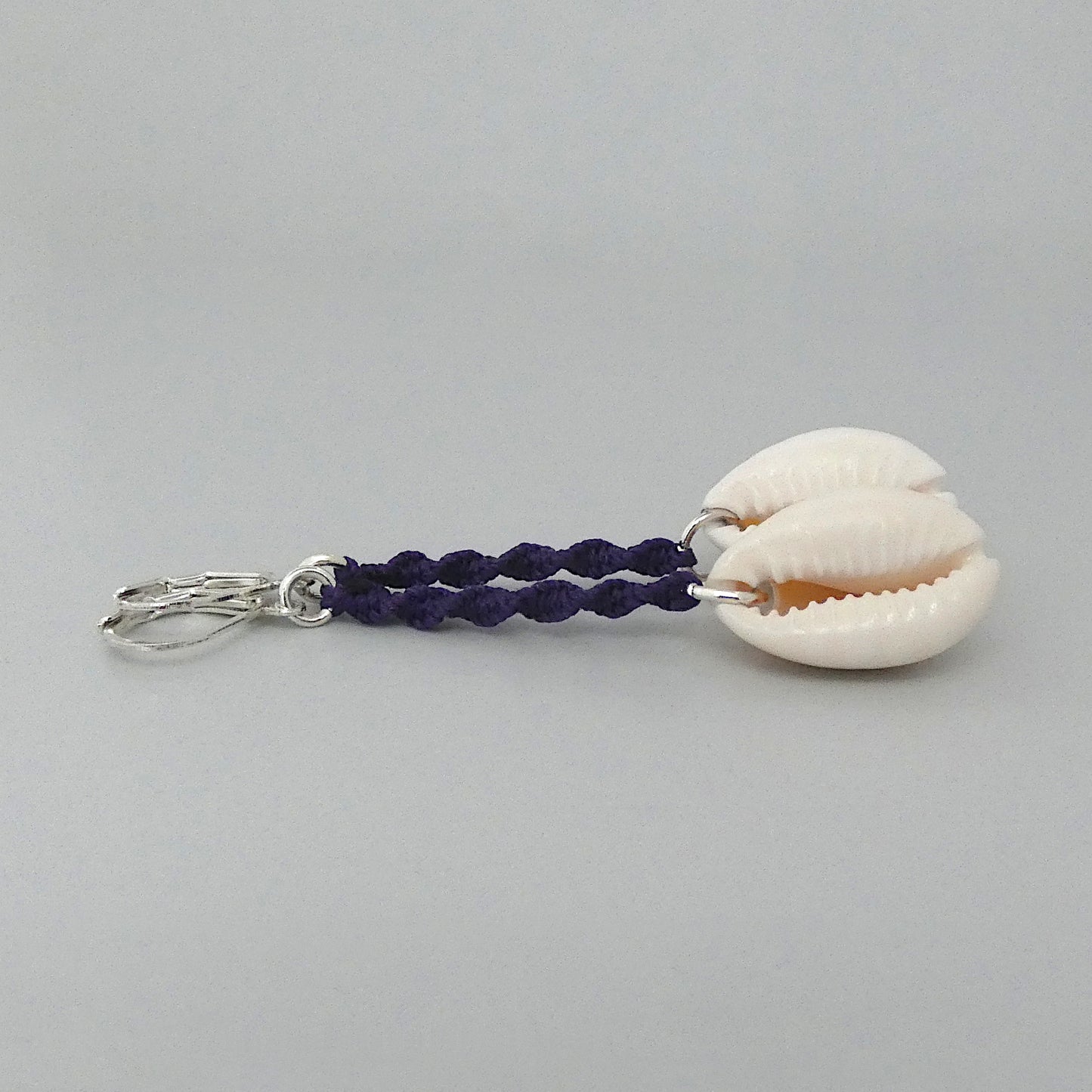 Silver plated leverback earrings with cowrie shells and dark purple macramé twist detail.