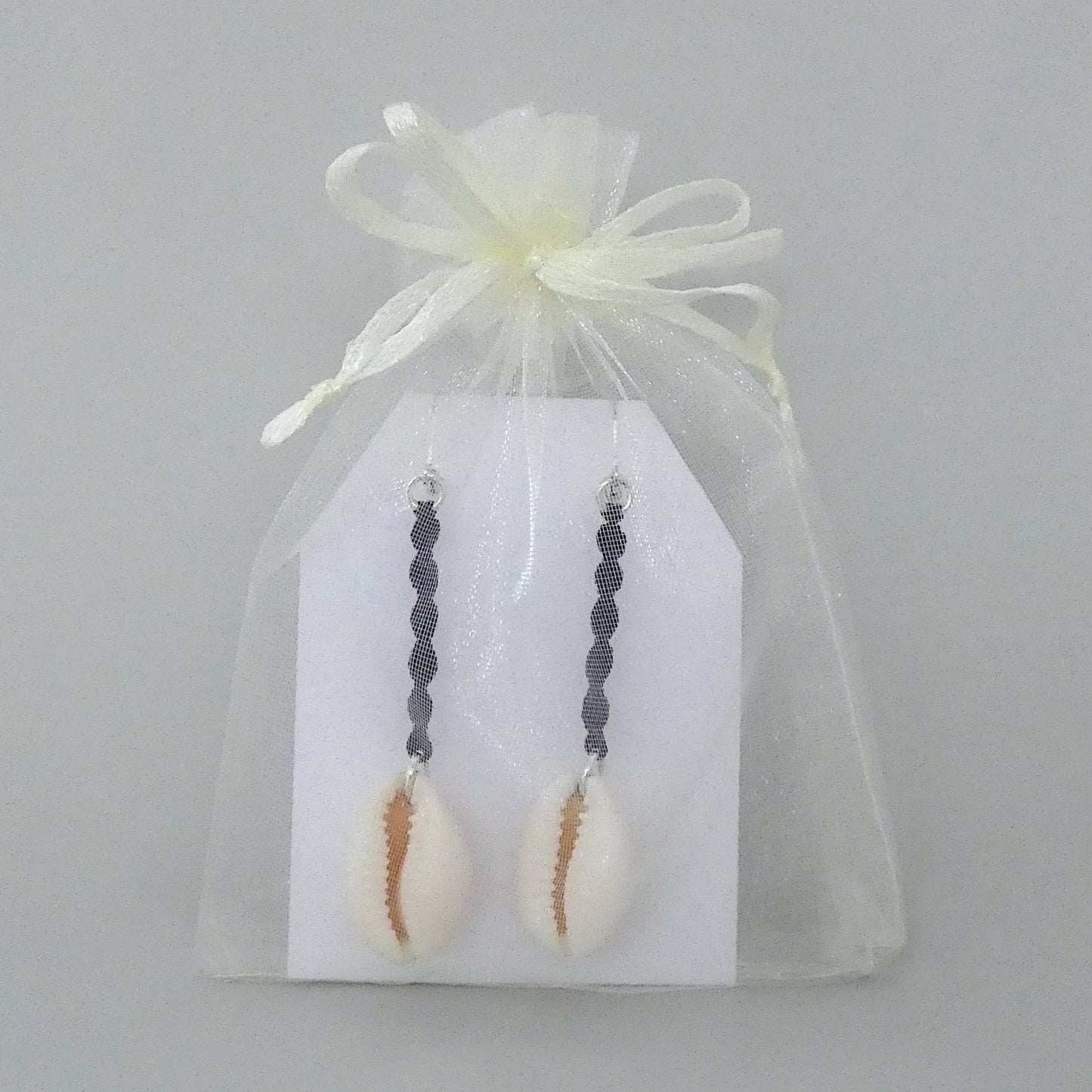 Silver plated leverback earrings with cowrie shells and dark purple macramé twist detail.