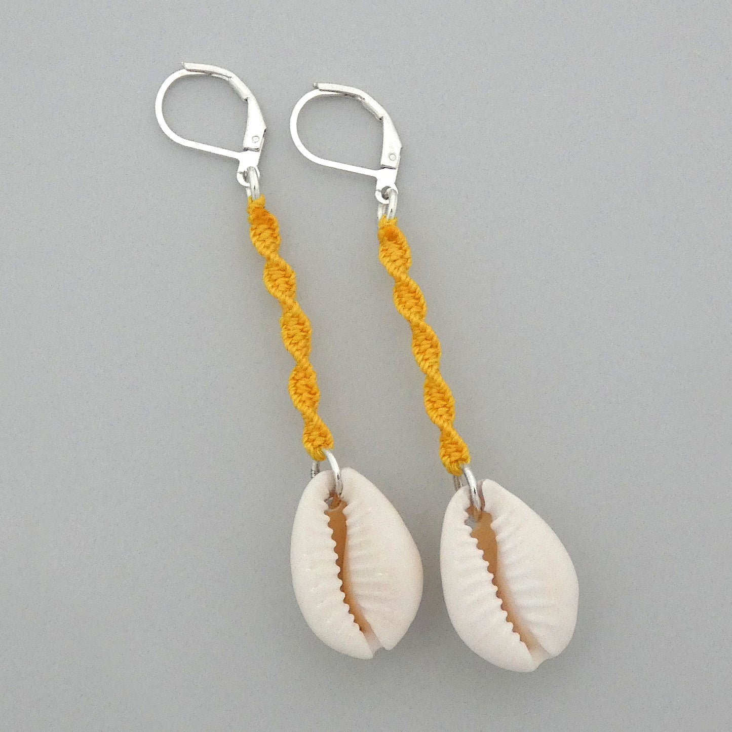 Silver plated leverback earrings with cowrie shells and golden yellow macramé twist detail.