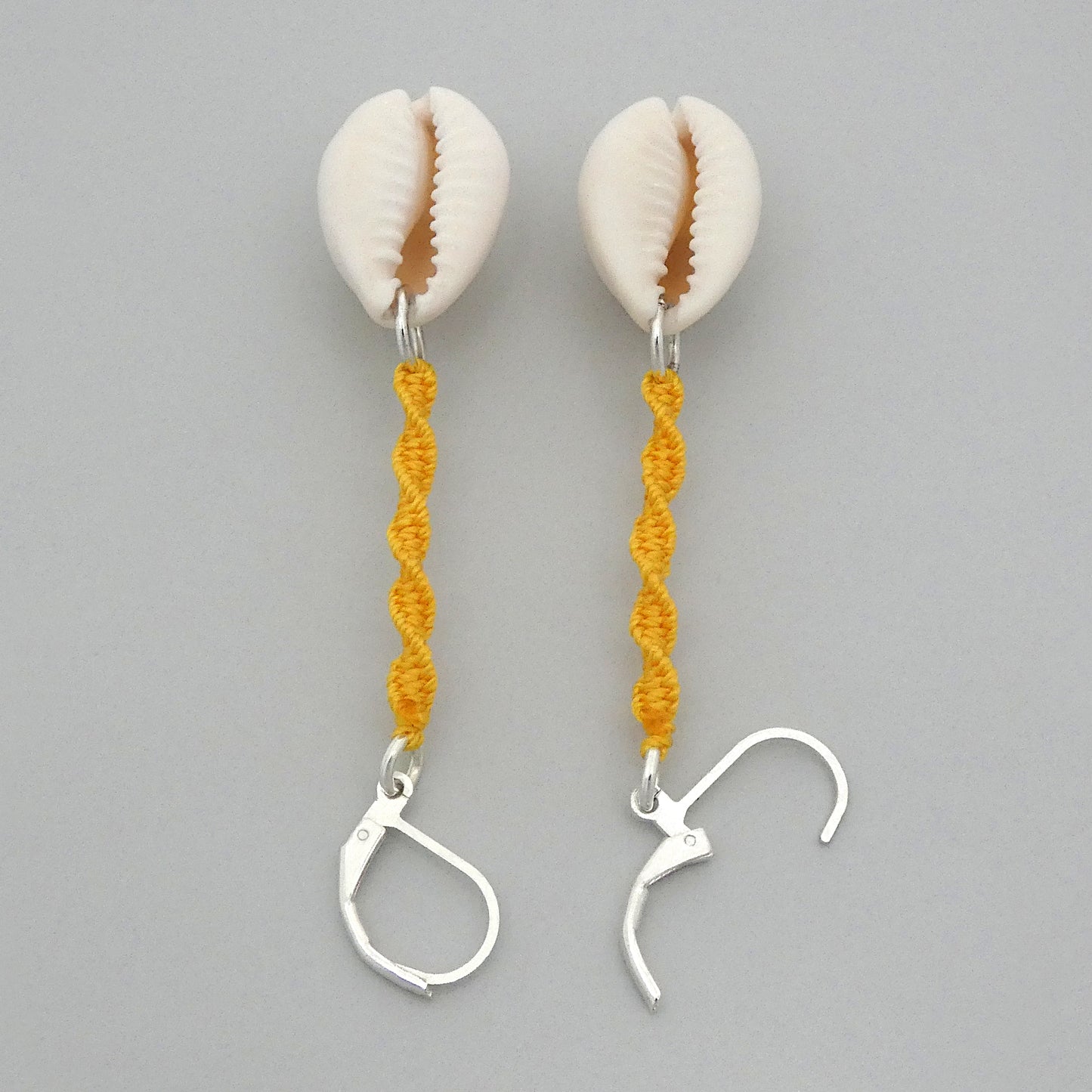 Silver plated leverback earrings with cowrie shells and golden yellow macramé twist detail.