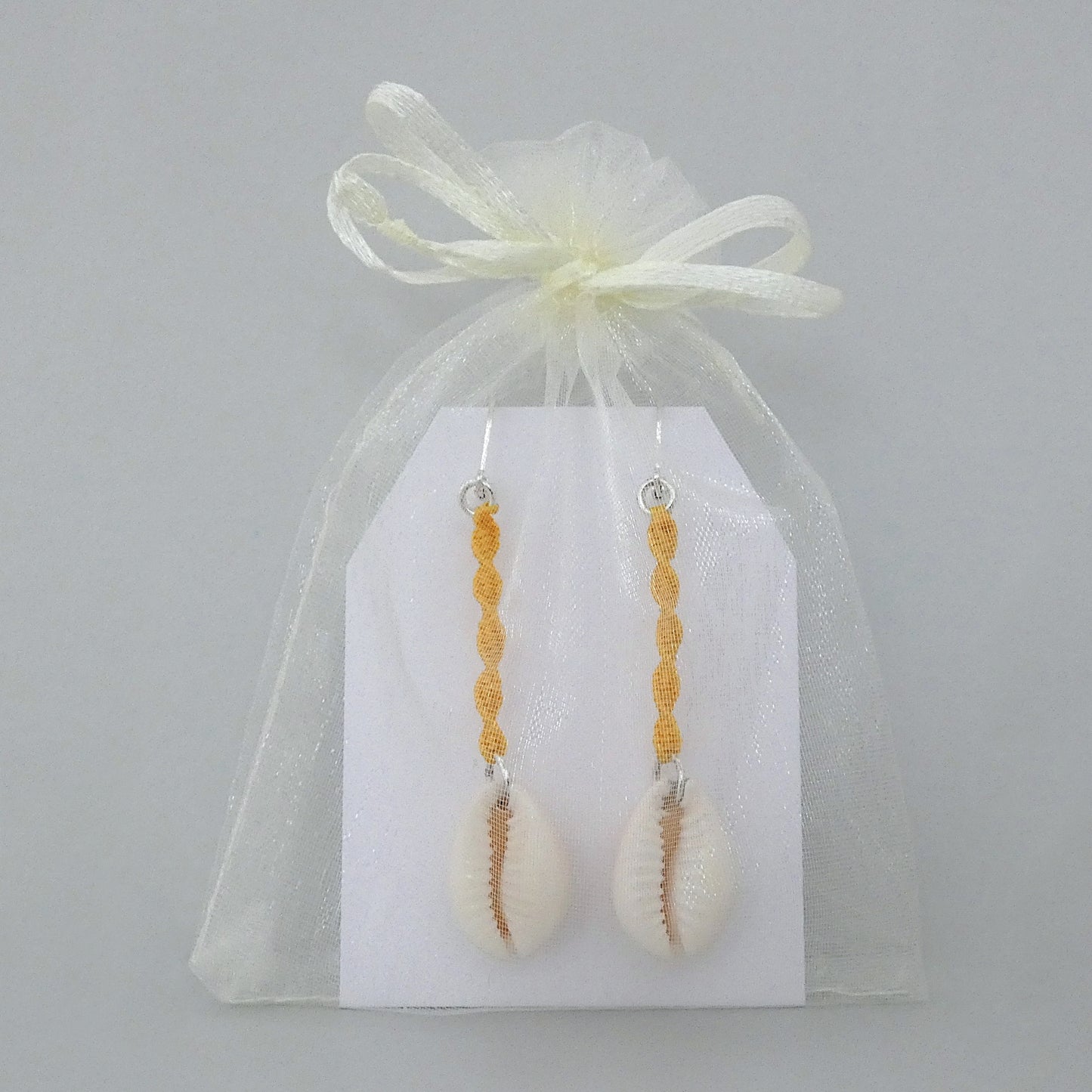 Silver plated leverback earrings with cowrie shells and golden yellow macramé twist detail.