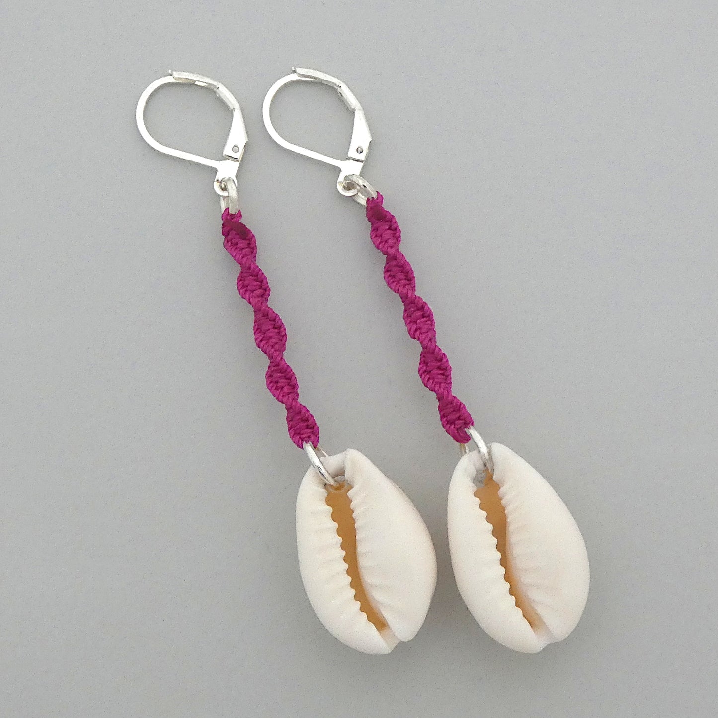 Silver plated leverback earrings with cowrie shells and magenta macramé twist detail.