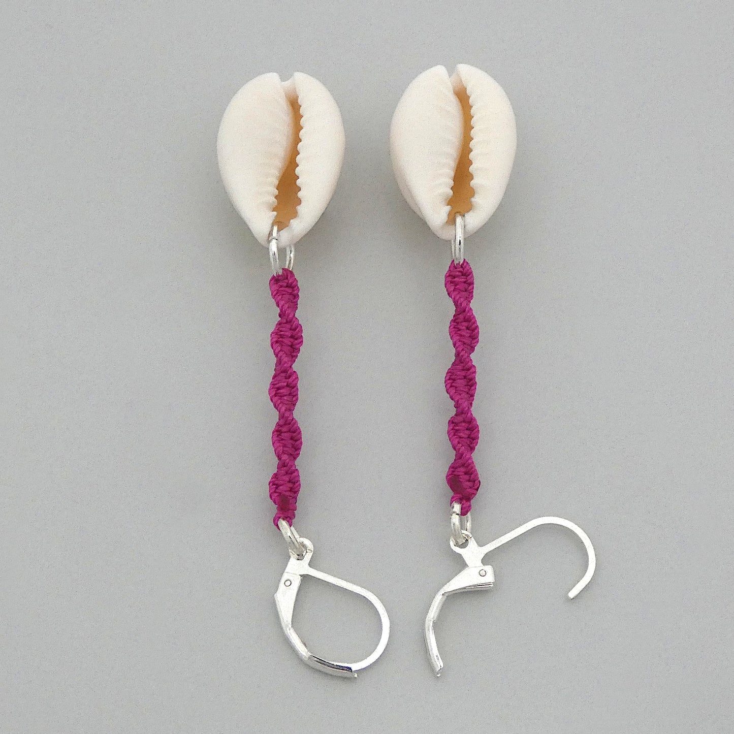 Silver plated leverback earrings with cowrie shells and magenta macramé twist detail.