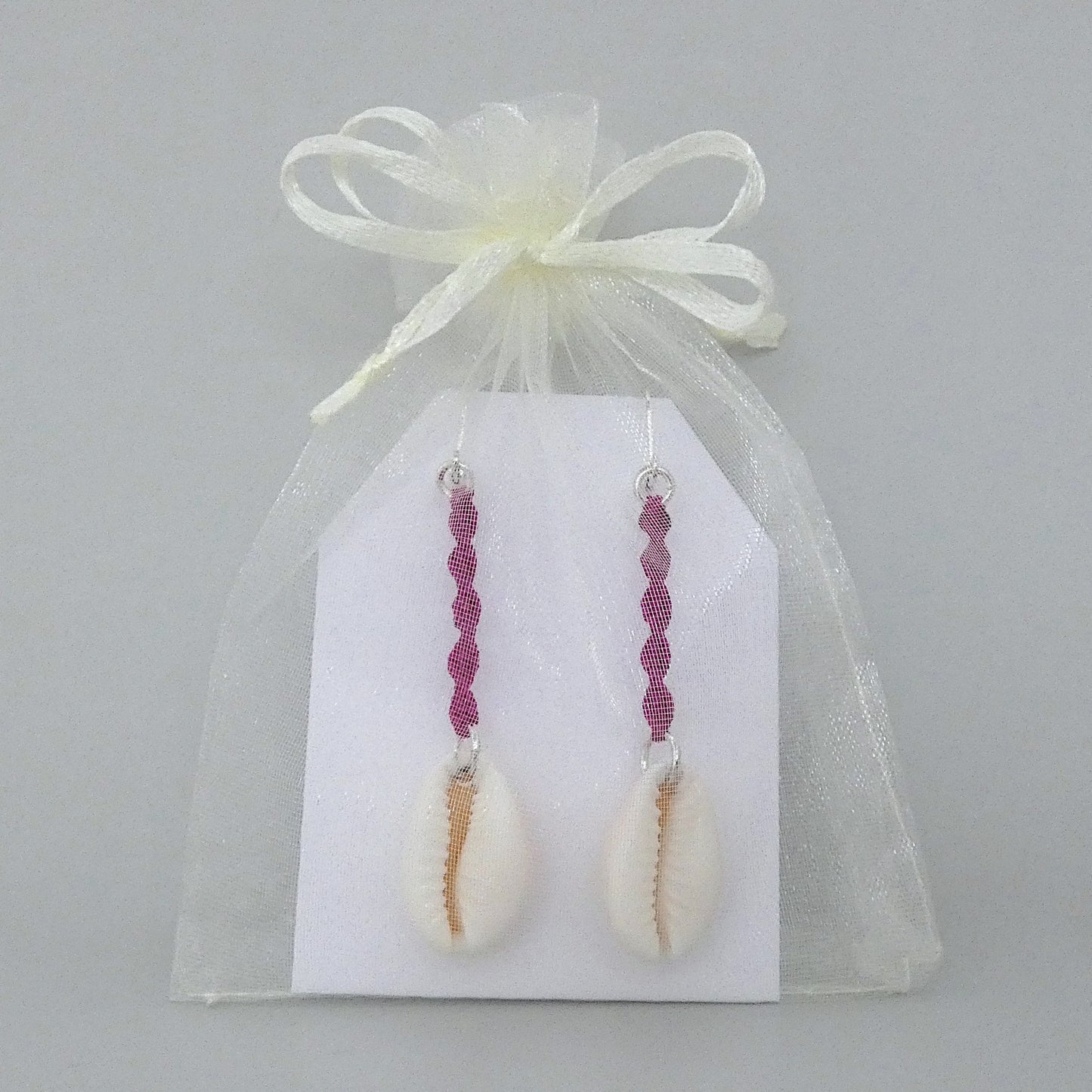 Silver plated leverback earrings with cowrie shells and magenta macramé twist detail.