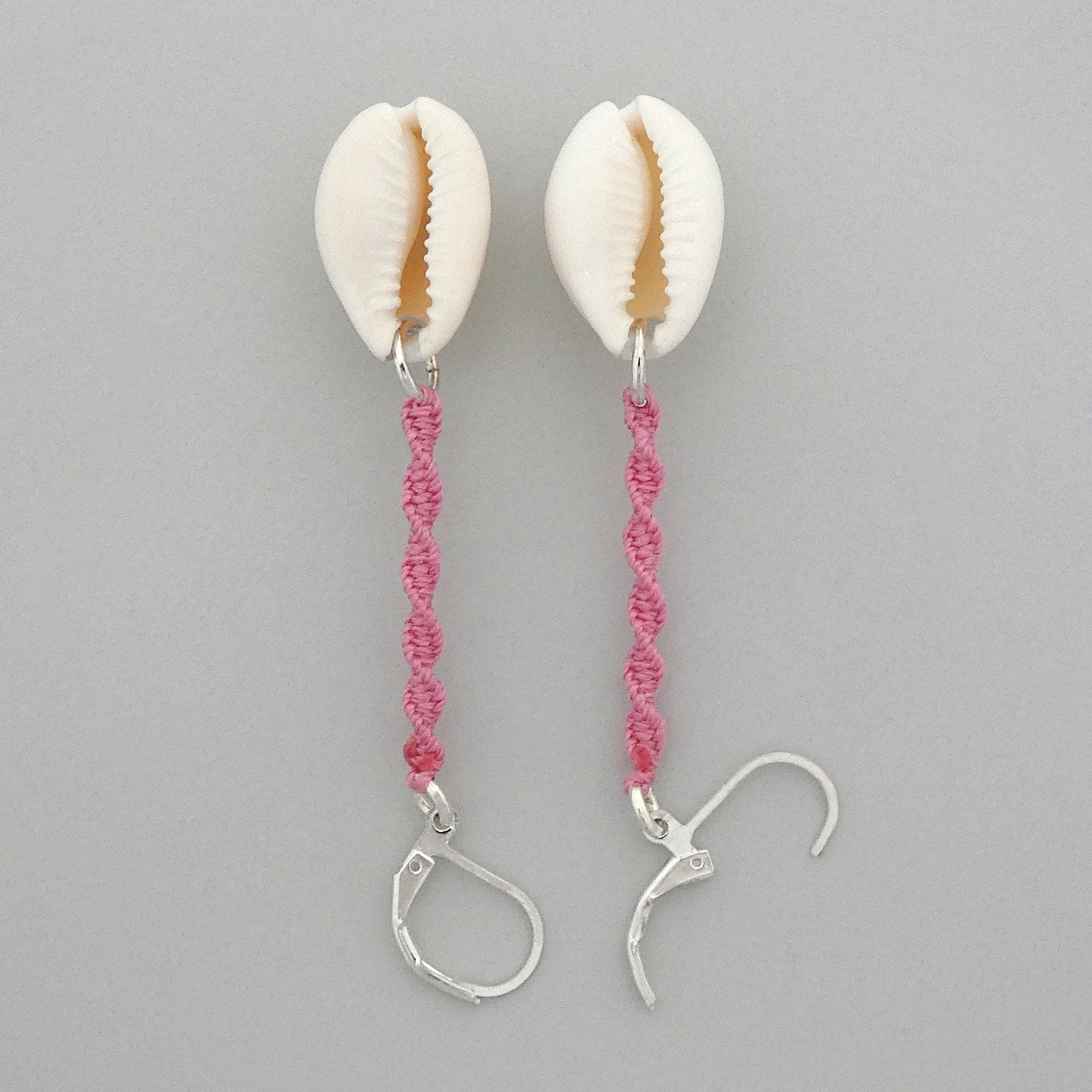 Silver plated leverback earrings with cowrie shells and pink macramé twist detail.