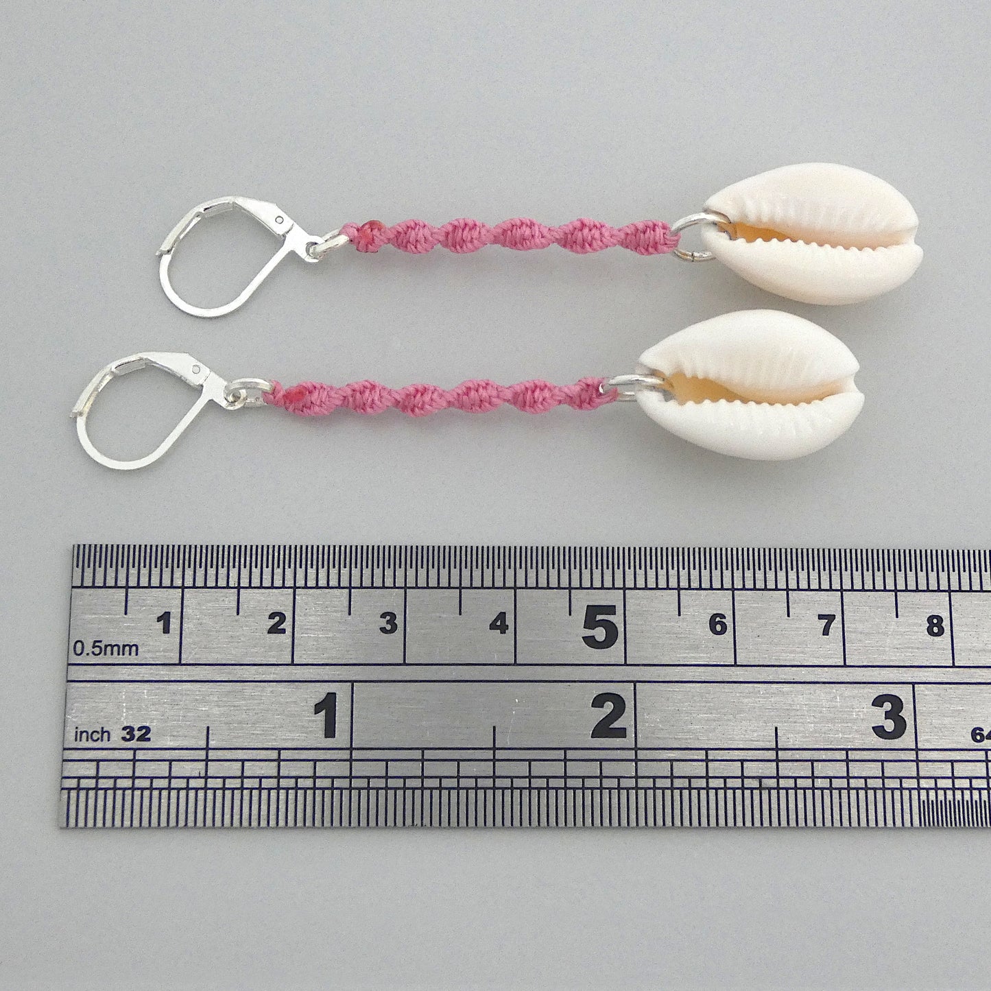 Silver plated leverback earrings with cowrie shells and pink macramé twist detail.