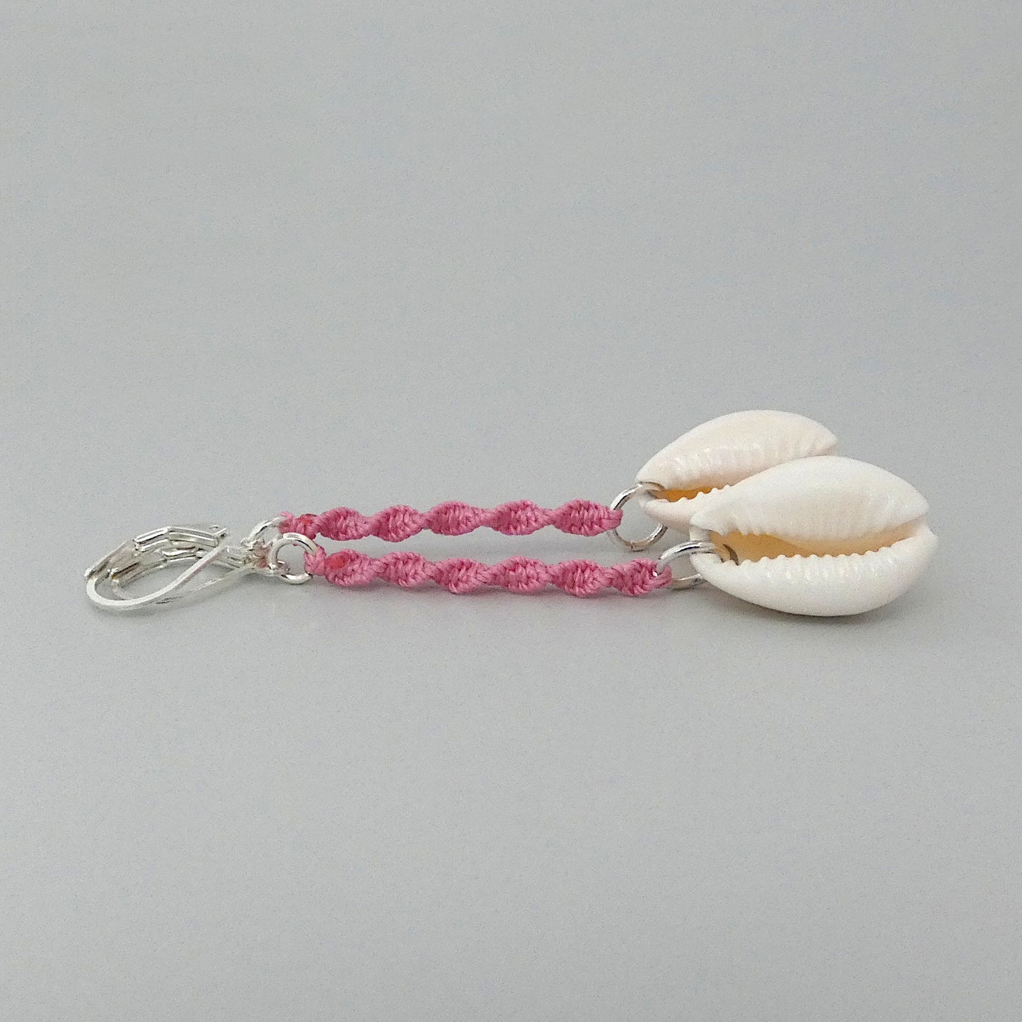 Silver plated leverback earrings with cowrie shells and pink macramé twist detail.