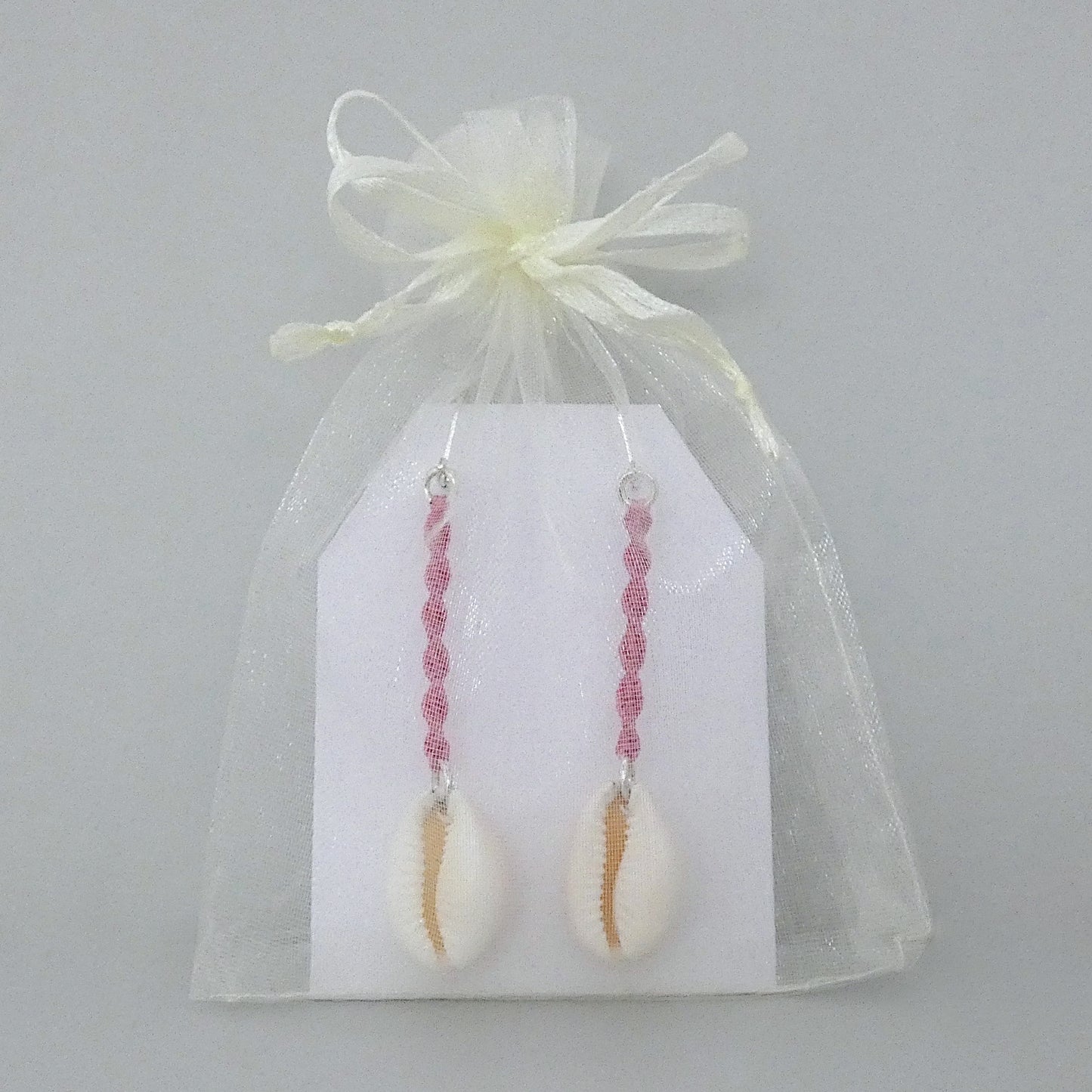 Silver plated leverback earrings with cowrie shells and pink macramé twist detail.