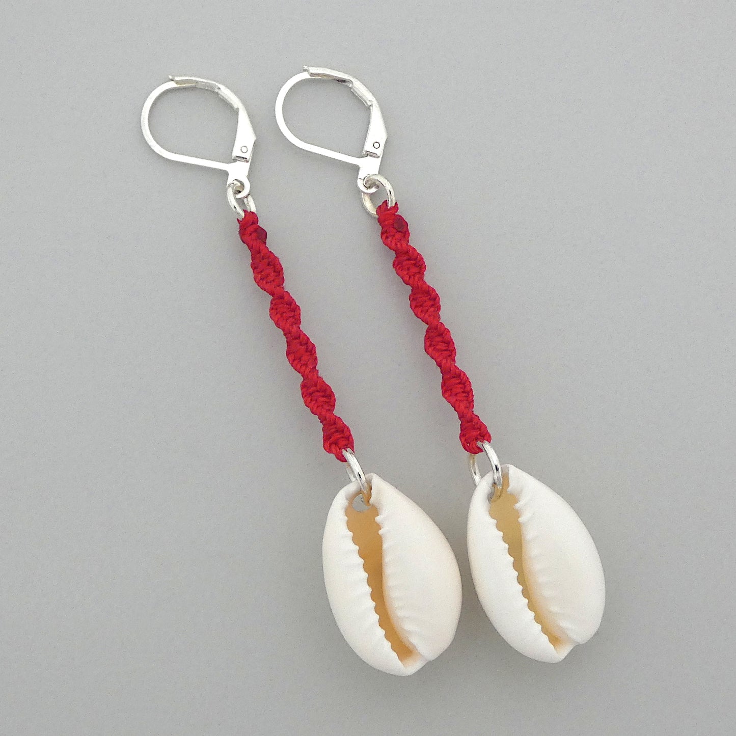 Silver plated leverback earrings with cowrie shells and bright red macramé twist detail.