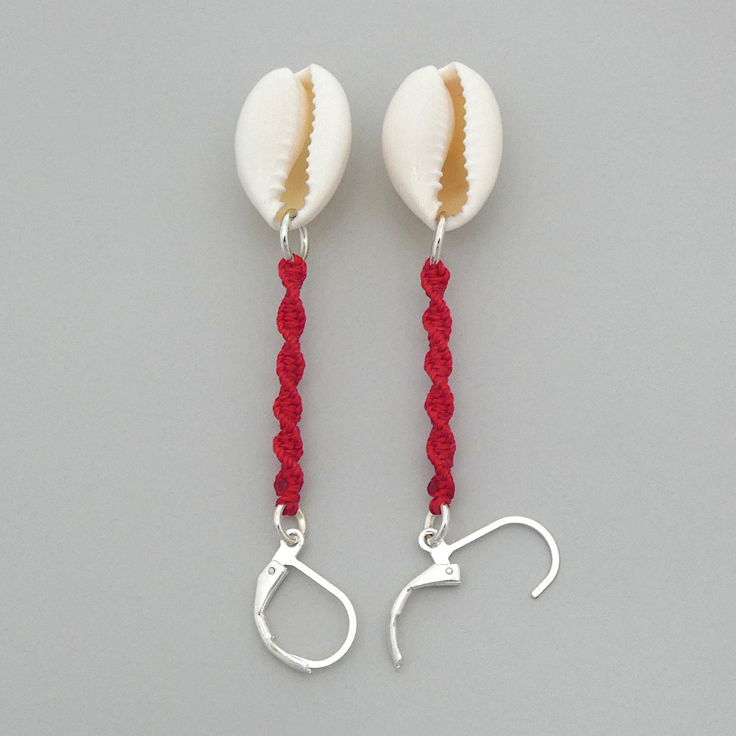 Silver plated leverback earrings with cowrie shells and bright red macramé twist detail.