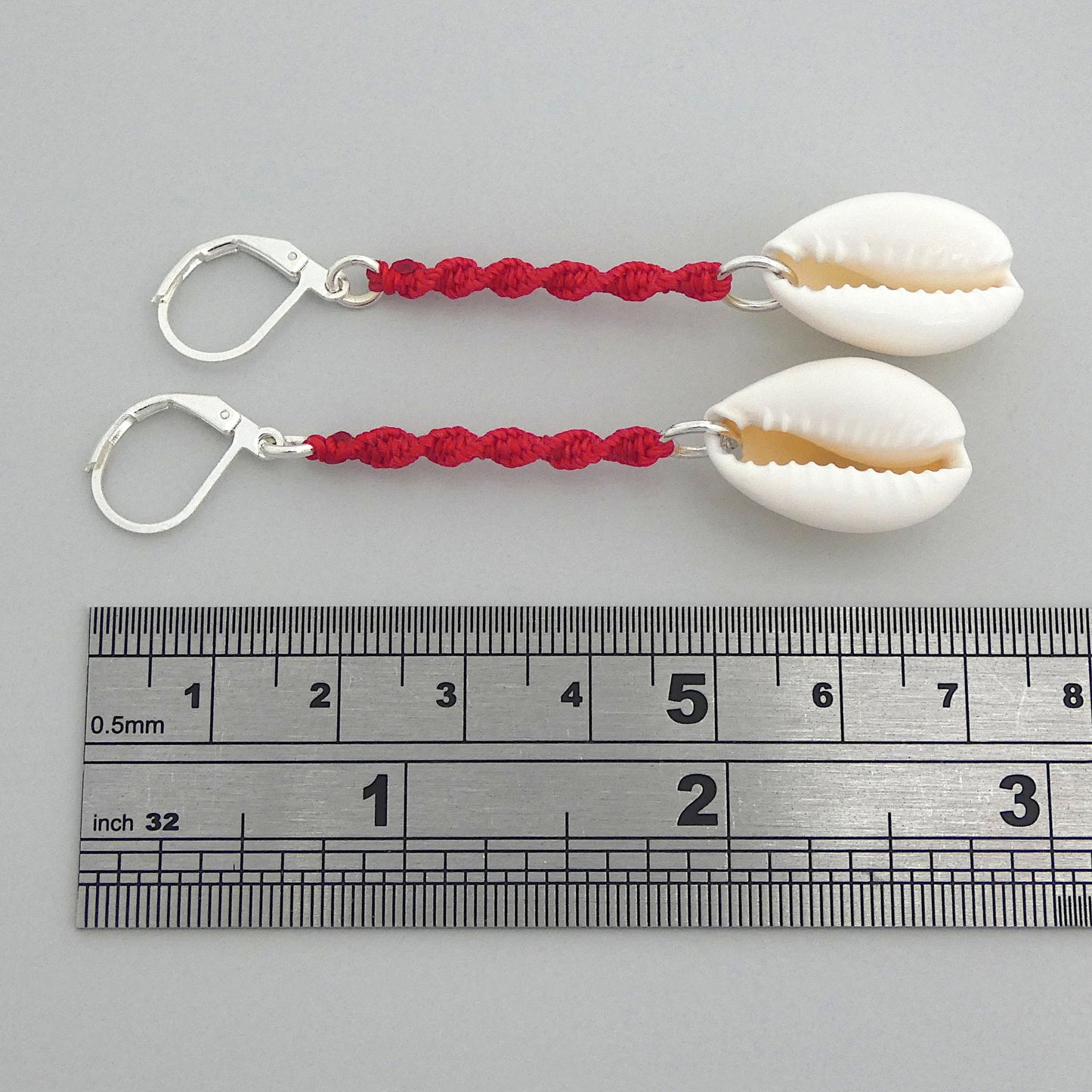 Silver plated leverback earrings with cowrie shells and bright red macramé twist detail.