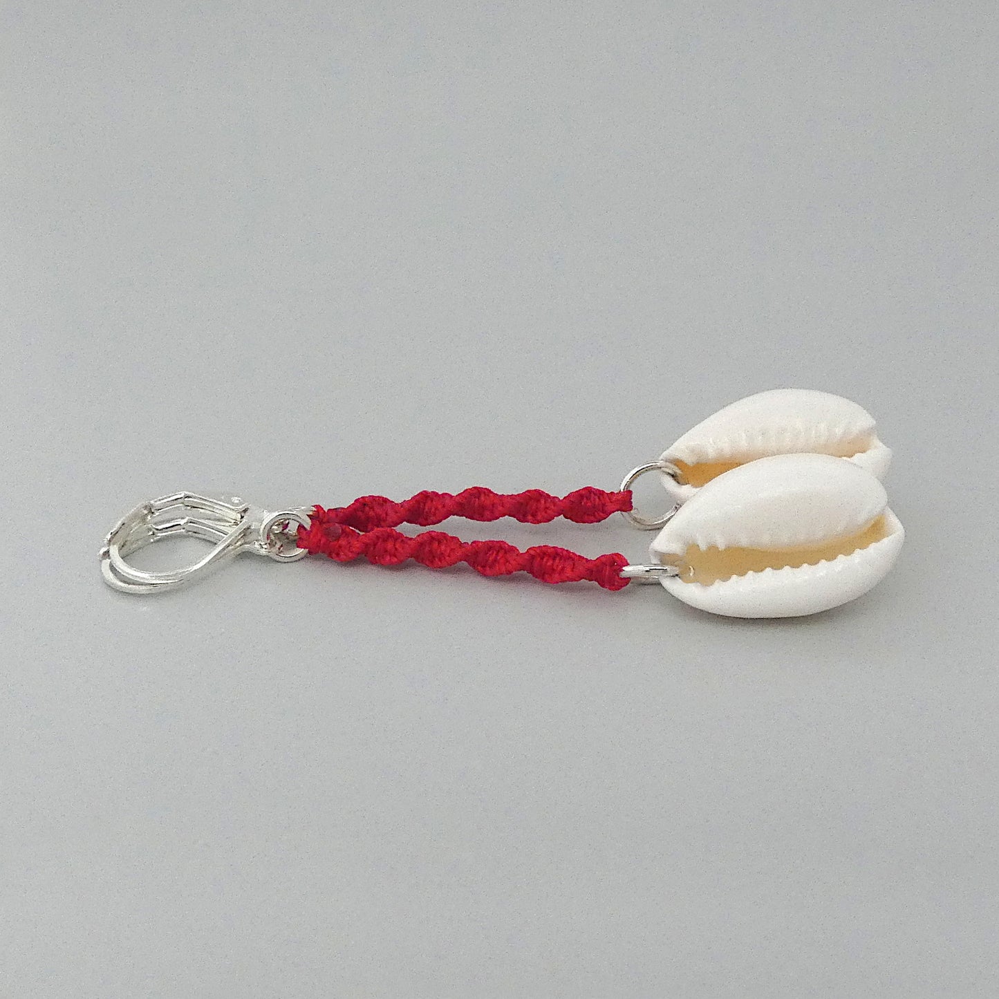 Silver plated leverback earrings with cowrie shells and bright red macramé twist detail.