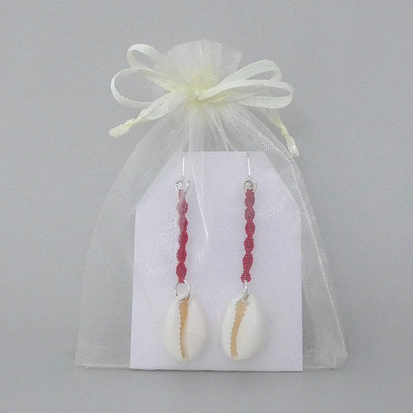 Silver plated leverback earrings with cowrie shells and bright red macramé twist detail.