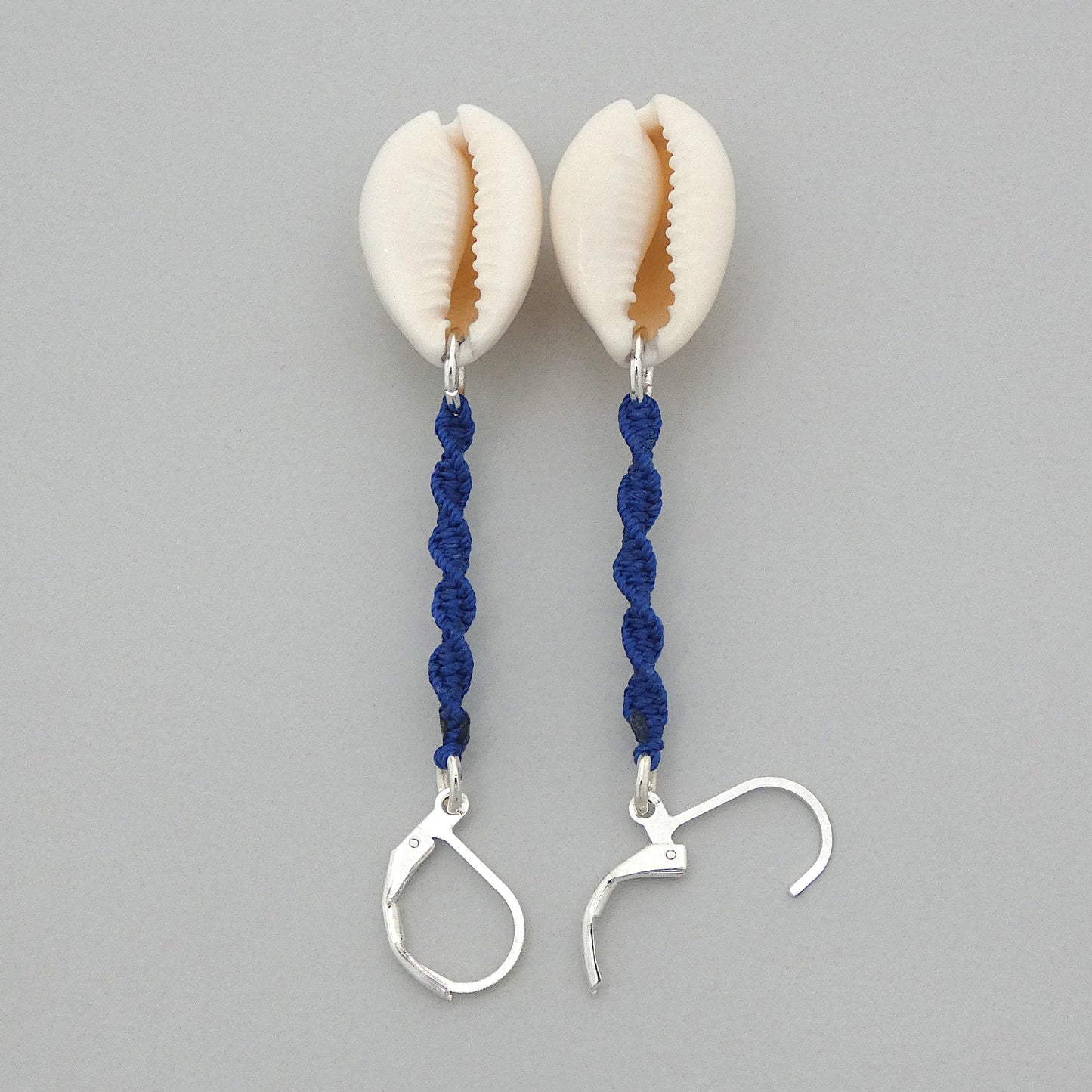 Silver plated leverback earrings with cowrie shells and royal blue macramé twist detail.