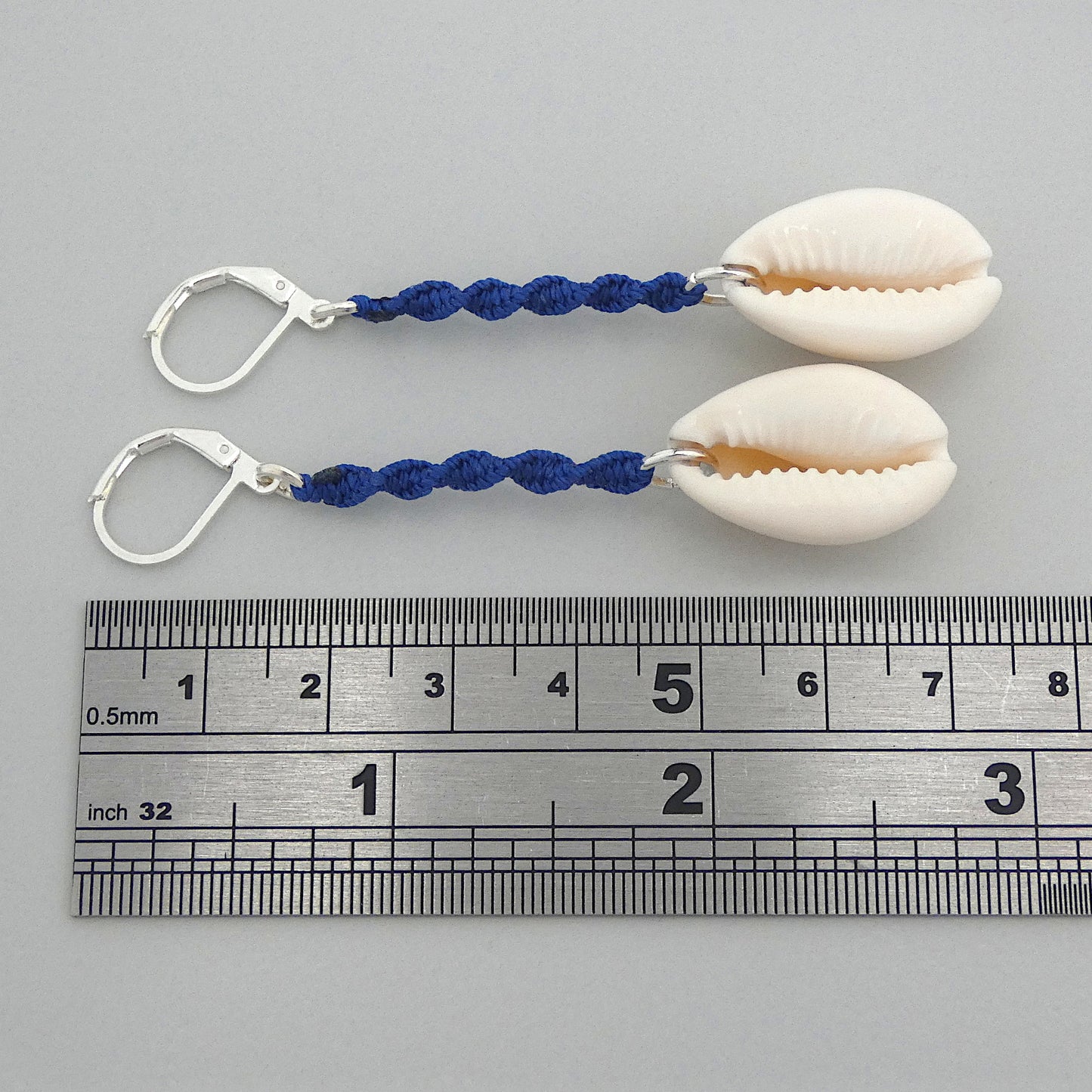 Silver plated leverback earrings with cowrie shells and royal blue macramé twist detail.