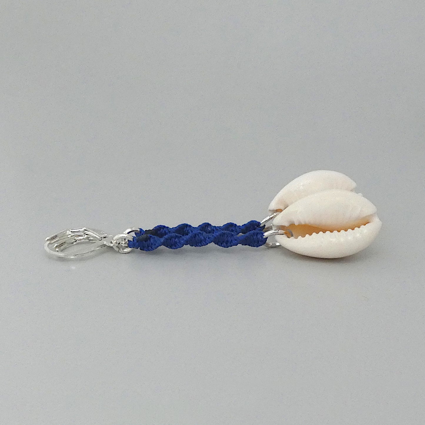 Silver plated leverback earrings with cowrie shells and royal blue macramé twist detail.