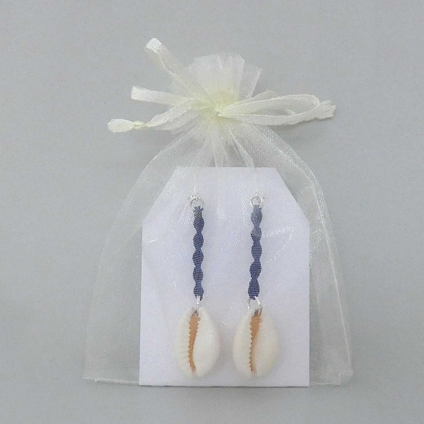 Silver plated leverback earrings with cowrie shells and royal blue macramé twist detail.