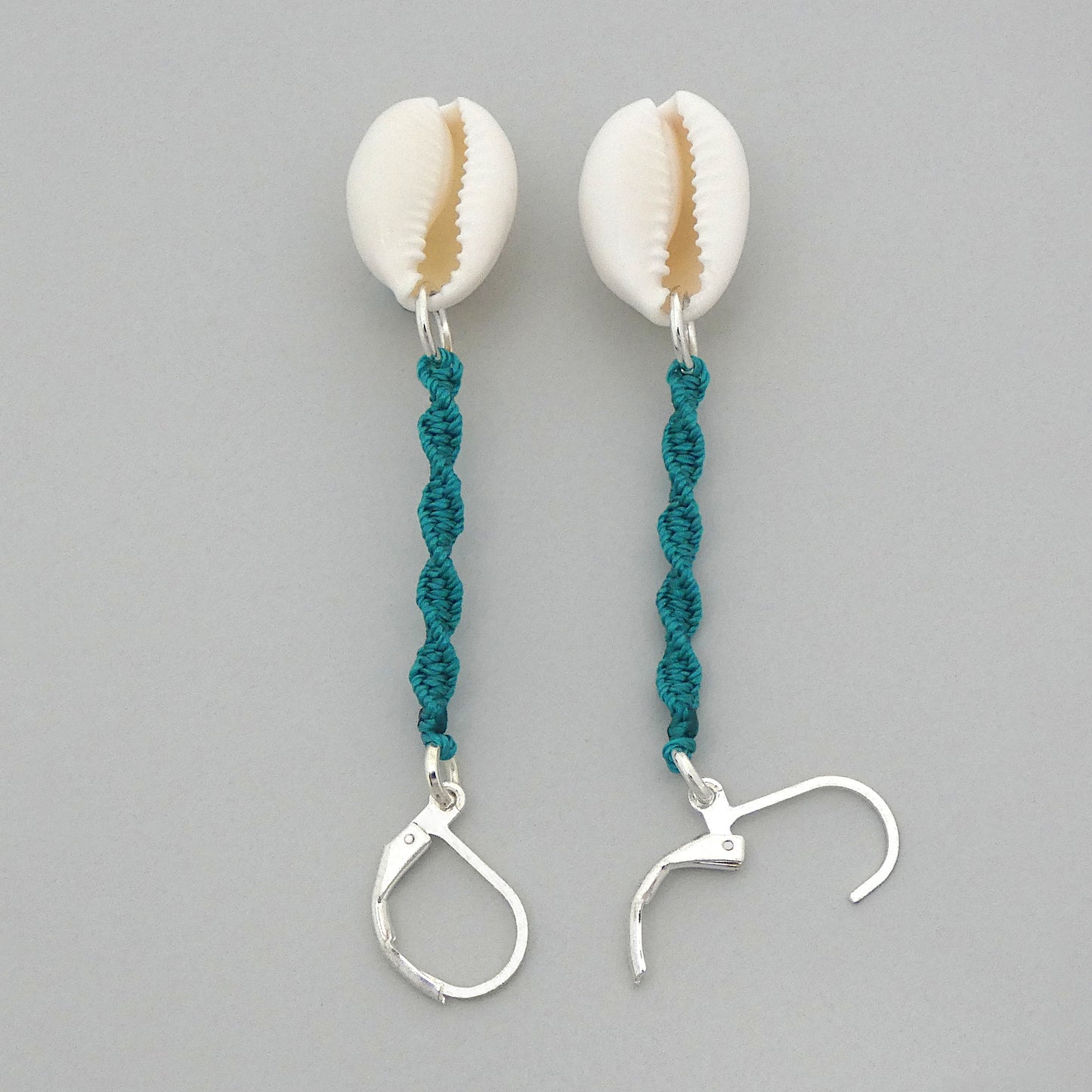 Silver plated leverback earrings with cowrie shells and teal green macramé twist detail.