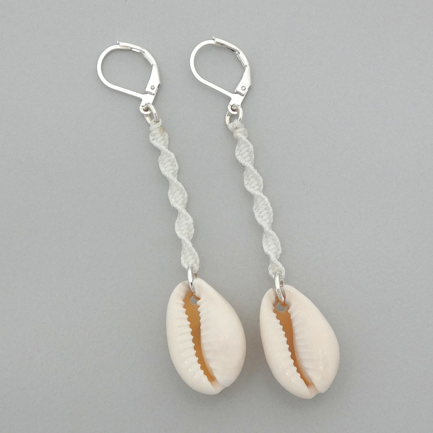 Silver plated leverback earrings with cowrie shells and white macramé twist detail.