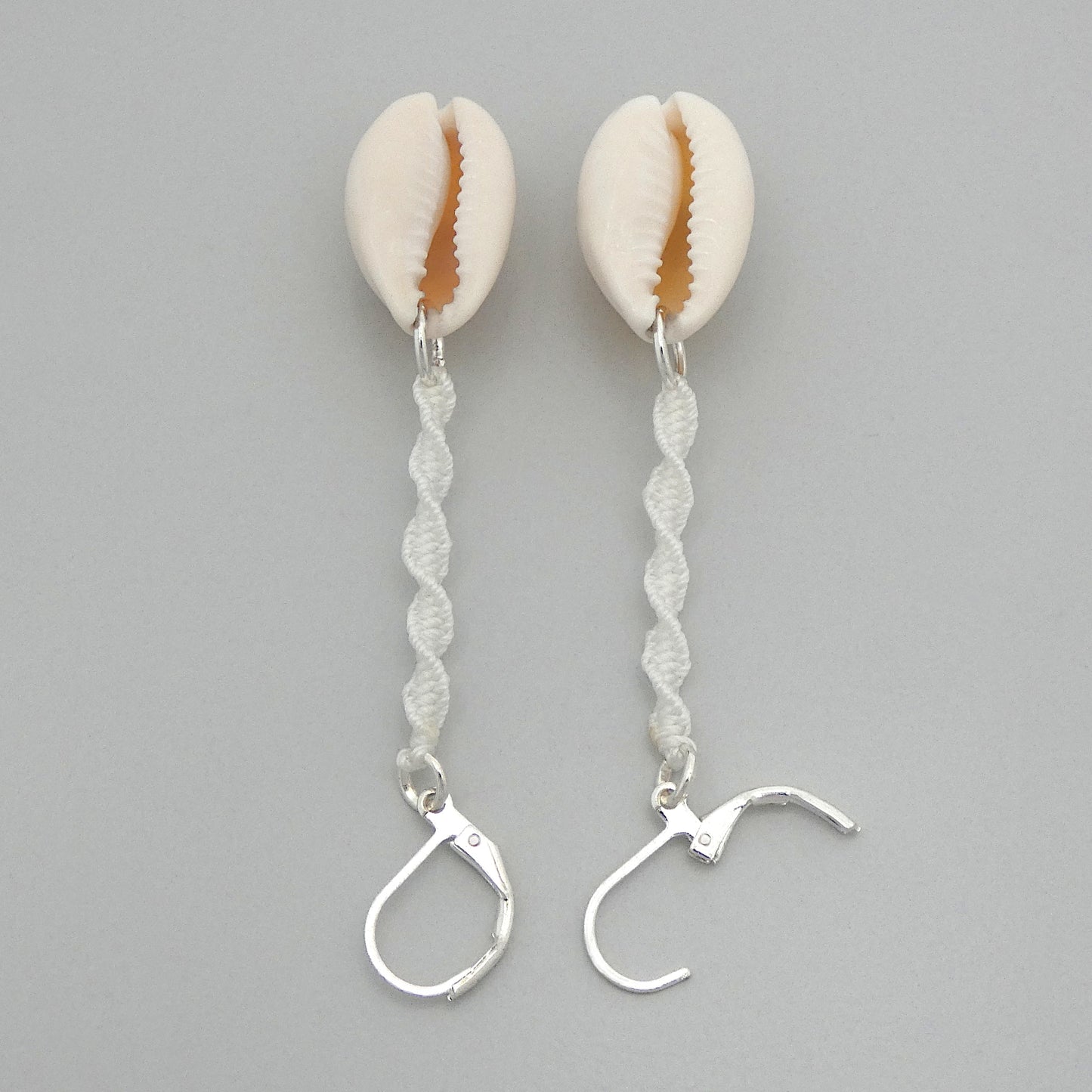 Silver plated leverback earrings with cowrie shells and white macramé twist detail.