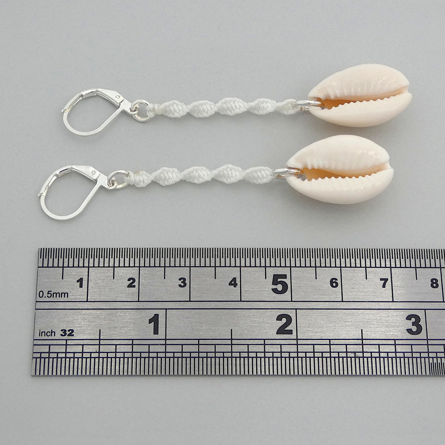 Silver plated leverback earrings with cowrie shells and white macramé twist detail.