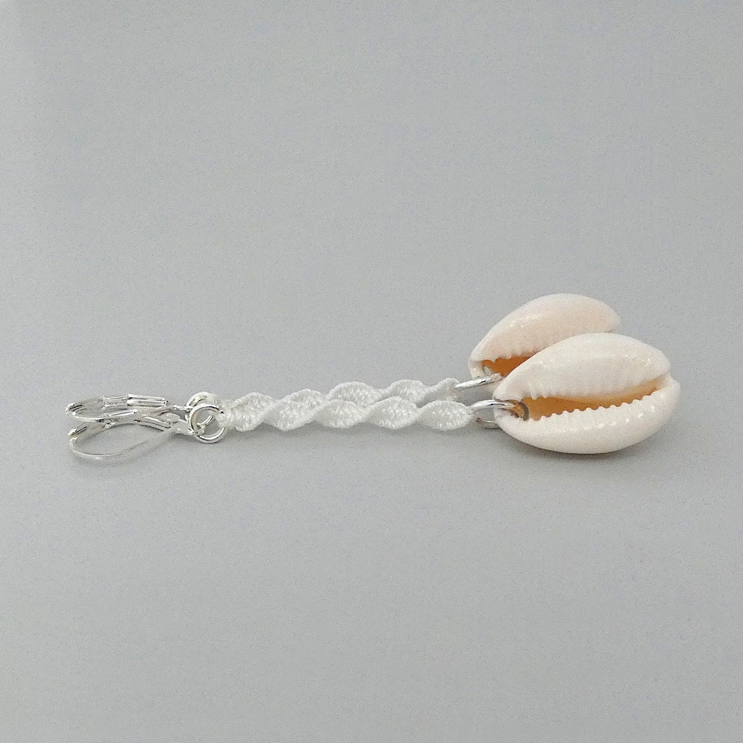 Silver plated leverback earrings with cowrie shells and white macramé twist detail.